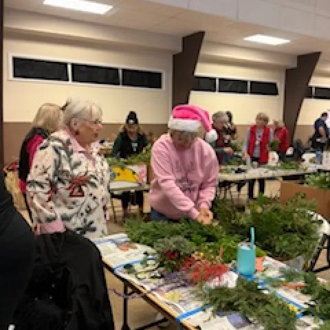 volunteer looks on as a woman is making a wreath