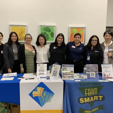 Eight women stand behind the Master Gardener and Farm Smart tables