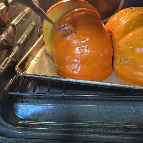 Pumpkin cut in half on baking sheet in oven