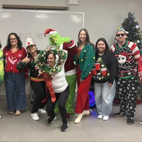 A group photo of people in holiday sweaters and costumes