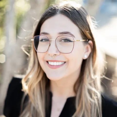 white woman with long brown hair in a black shirt and glasses smiling