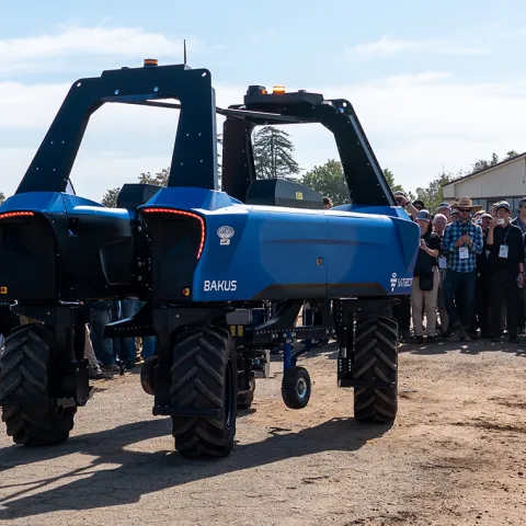 An autonomous agricultural robot demonstrated outdoors as attendees gather to observe during a UC ANR Innovate field event