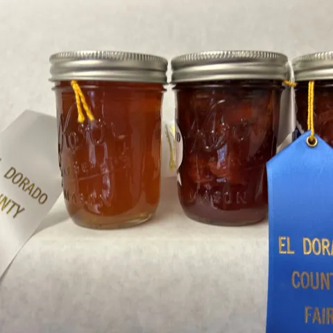 three jars of jellies with county fair ribbons