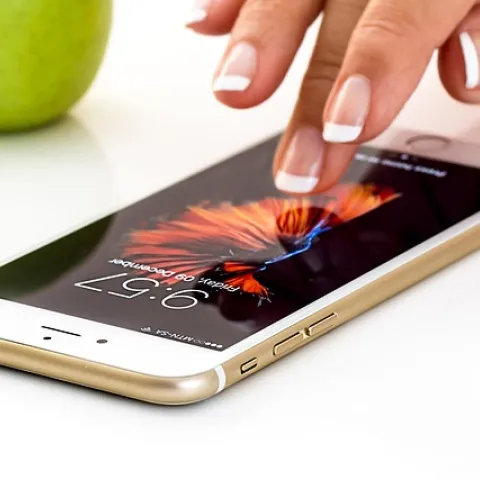 a finger manipulates an app on an iPhone sitting on a surface