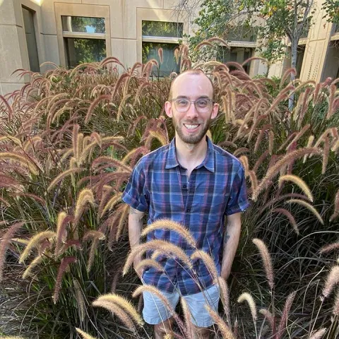 Justin stands outdoors among landscape plants