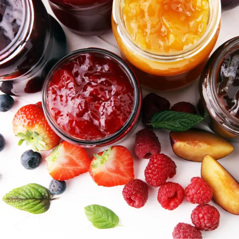 Top view of jars of jam with fruit.