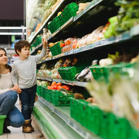 Mother and son shopping in the produce section of a grocery store.