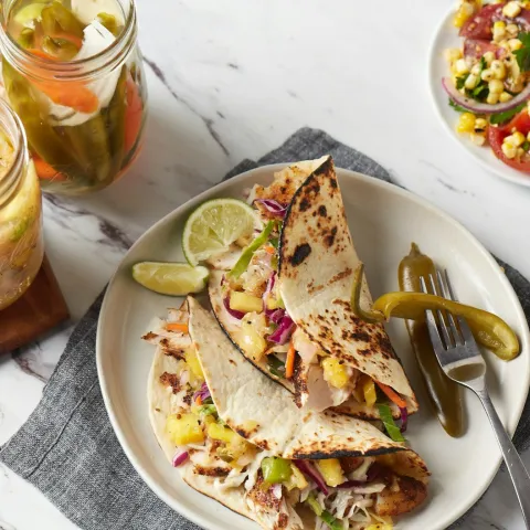 two jalapeno tacos on a plate with a fork full of jalapenos and lime wedges