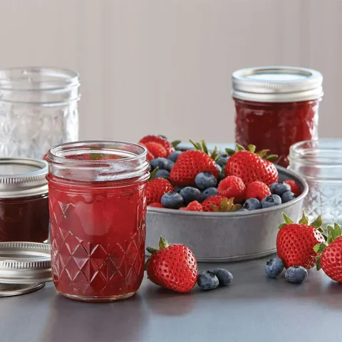 jar of berry jam with bowl of berries next to it