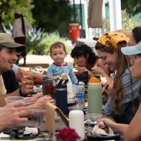 group of people sitting at a picnic table engaging with each other