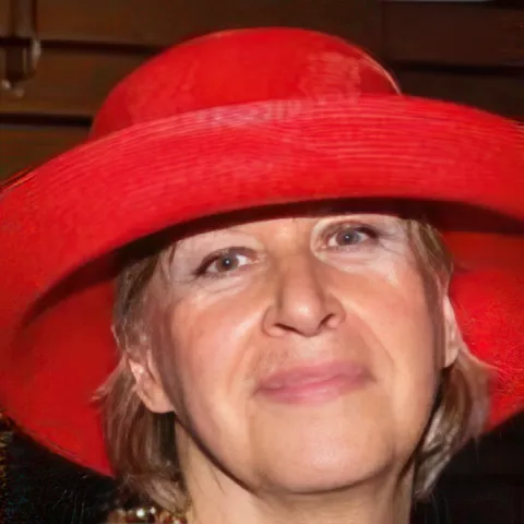 Debra is a smiling woman in a red hat