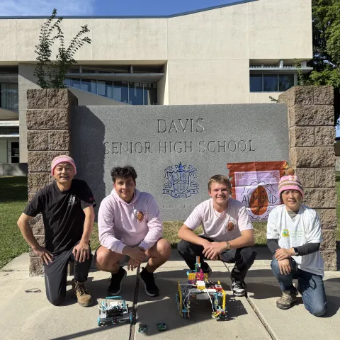 Almond Robotics, Modular Learning, Inc. team crouch by the Davis Senior High School sign