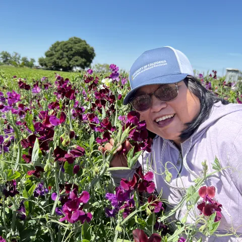 Fam Lee poses up-close with flowers in a field