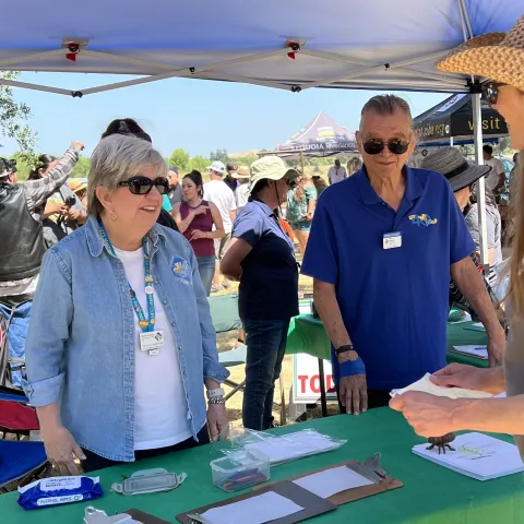 2 master gardeners helping an adult at the Go Native booth