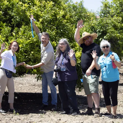 Master Gardeners waving at camera in orchard