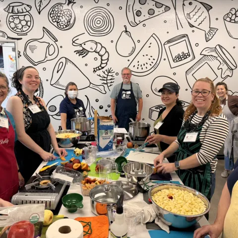 group of smiling people cooking with pots and pans