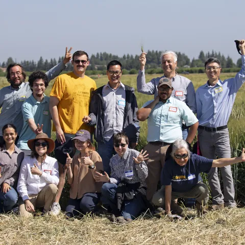 people smiling and waving at camera in a field