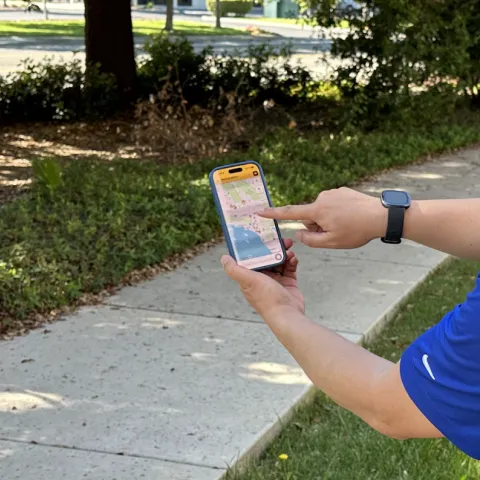 Disembodied hand points to flame image on a California map on a phone