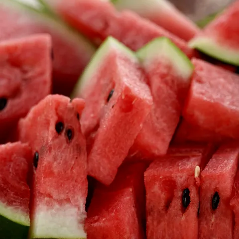 red watermelon with seeds cut into triangles with rinds on