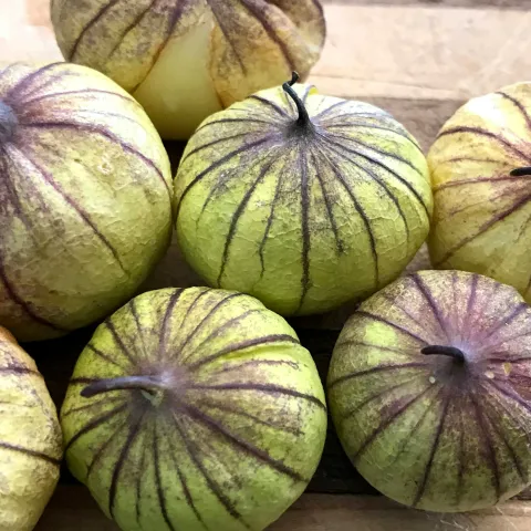 a pile of tomatillo fruit with green and purple variegated skin on