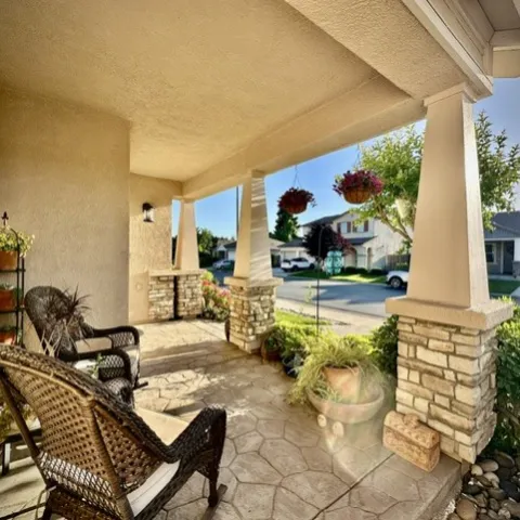Picture of a suburban front porch with green landscaping and outdoor furniture arranged on the porch.