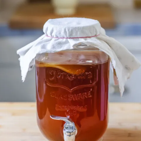 Large glass jar of kombucha with cloth cover
