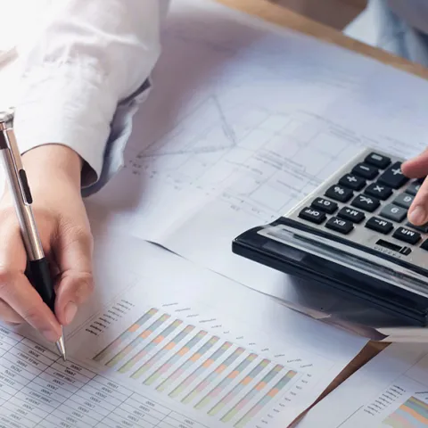 person engaged in bookkeeping with notes and a calculator