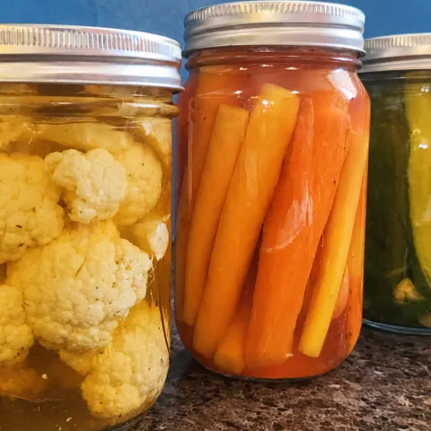 three jars containing pickled vegetables