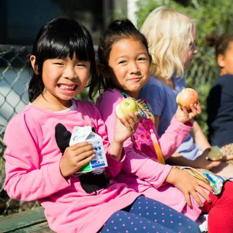 Children sitting eating lunch outdoors
