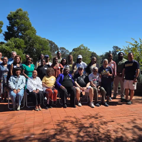 Standing and sitting in chairs on a back patio are 25 Black adults and college students