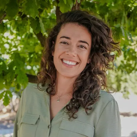 Headshot of Kelsie with brown curly hair and a green blouse. 