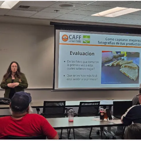 Kitchen Table Advisor staff presenting in a room next to a screen with a PowerPoint slide