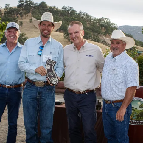 A group of four people stand holding an award