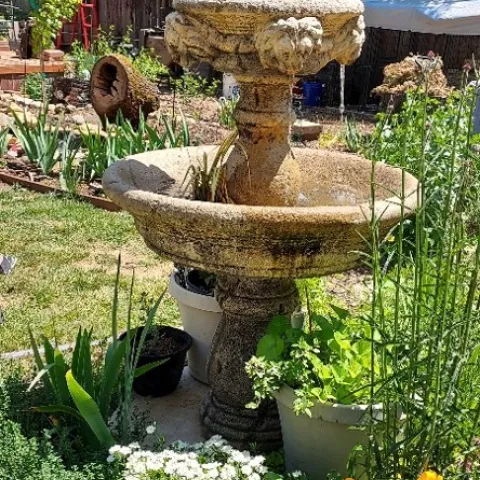 Picture of a multi-tiered cement fountain in a garden.