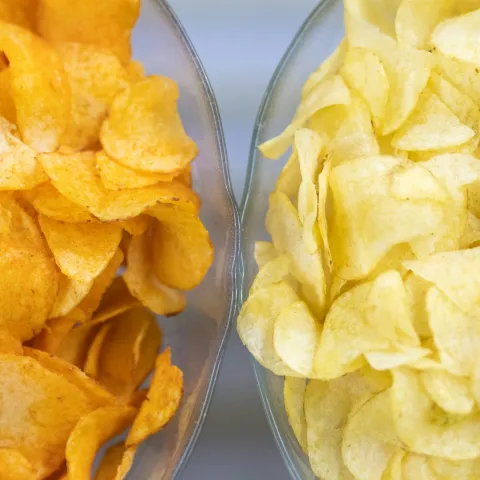 Two bowls of chips, one orange tinged and one plain yellow