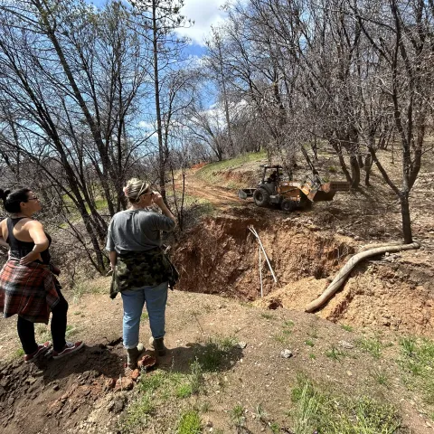 Two people examine erosion damage on a forest road.