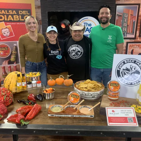 Four people standing at a market booth with salsa tastings