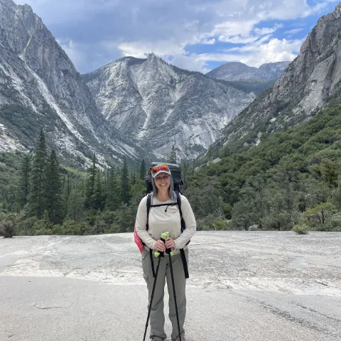 Kristin Polidoro stands with hiking poles, with Kings Canyon behind her and the South Fork of the Kings River below, unseen