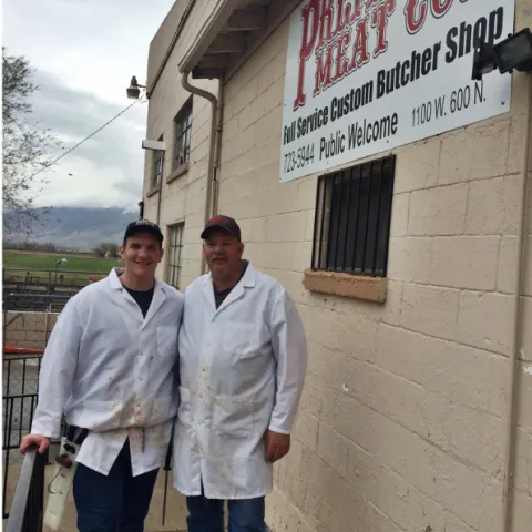 Two people standing outside a butcher shop