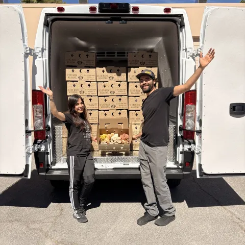 Two people standing next to a truck filled with boxes