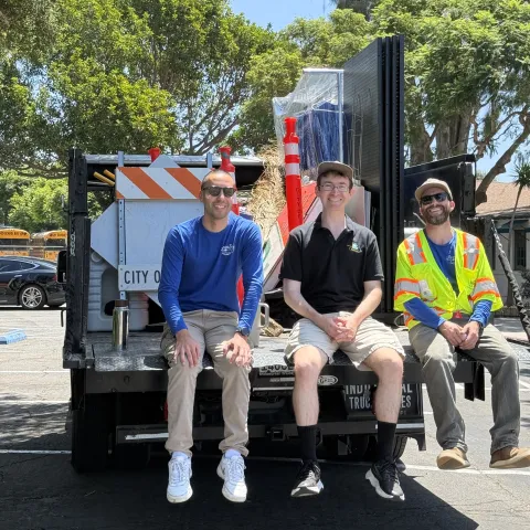 Jason Scott-Sheets, middle, sits with two Public Works colleagues at the back of a truck filled with tools and signs during a community cleanup event