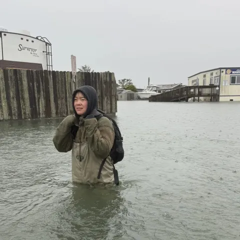 A woman in a rain coat in a flooded area