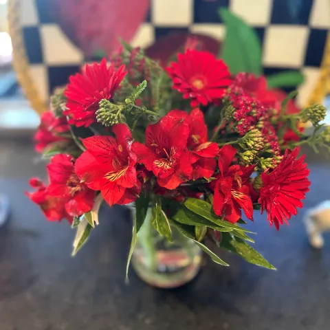 vase of red cut flowers including Gerbera daisies, Alstroemerias, and Achillia