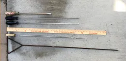 Five soil moisture probes of varying lengths, three of them long screwdrivers, alongside a yardstick for scale, laid on concrete.