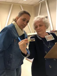 Two people looking at insects in a vial.