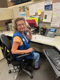 Smiling woman sitting in a chair at a desk.