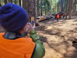 A teacher uses a compass to traverse through the forest