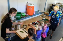 youth and adults making pickles together in a kitchen
