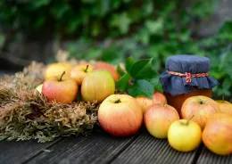 apples displayed on wooden table with a mason jar of preserved apples