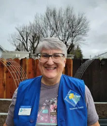 Smiling master gardener wearing a blue vest.